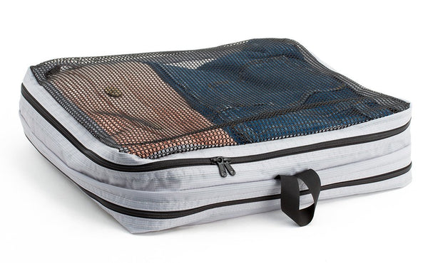 A filled and zipped closed Northwest Sky (light grey) Aether Large Laundry Aeronaut 45 Packing Cube mesh side up.